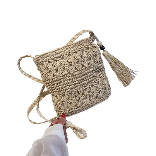 Beige woven bag with tassel held by a hand on a white background