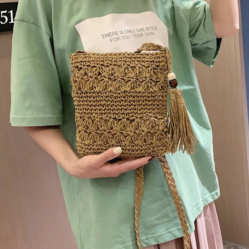 Person holding a woven bag with tassels, wearing a green shirt.