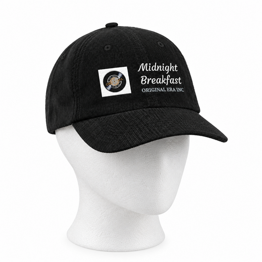 A black baseball cap displayed on a white mannequin head against a plain white background. The cap features a white embroidered logo that reads 'Midnight Breakfast ORIGINAL SEA INC.